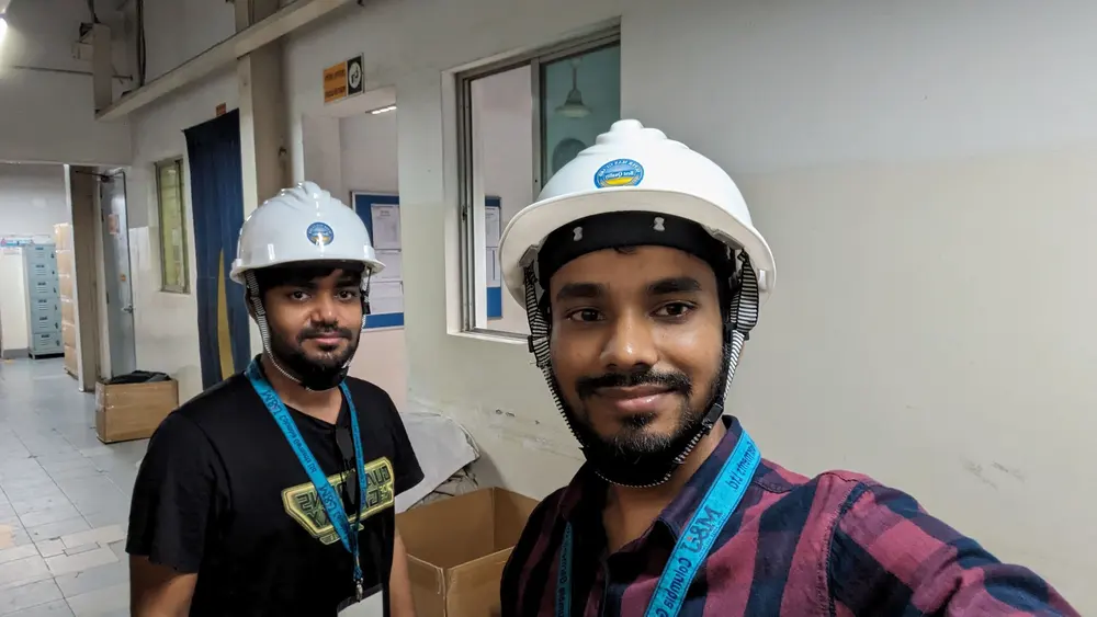 Two engineers in hard hats inside a factory corridor