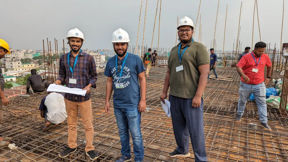 Three engineers in hard hats reviewing drawings on a reinforced slab