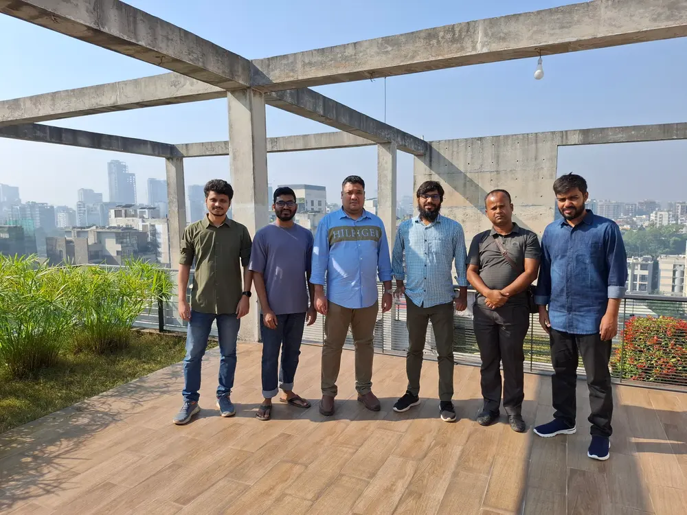 Ali Mahasin with five colleagues on a concrete-framed rooftop terrace overlooking the city